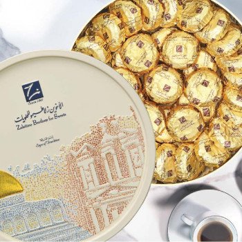 Top view of Zalatimo Brothers Maamoul Dates tin next to a cup of Arabic coffee, showcasing luxury presentation.
