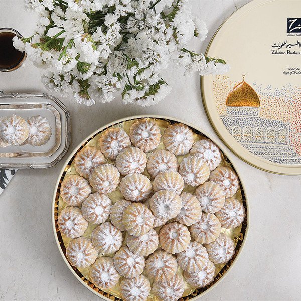 Assorted maamoul cookies in a golden gift box with a blend of date, pistachio, and walnut fillings.