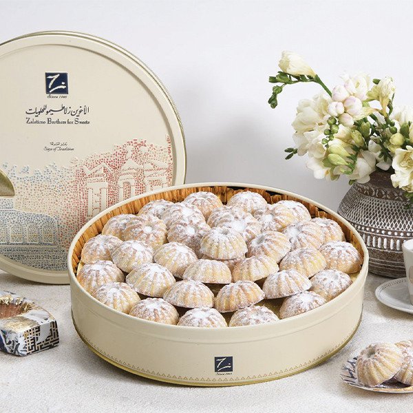 7Maamoul cookies on a traditional Arabic serving tray beside a Zalatimo Brothers branded tin, blending heritage and elegance.